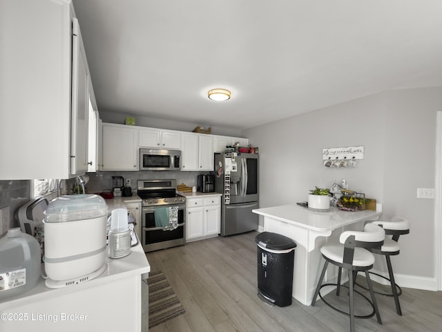131 Benelli Dr, Bardstown, KY 40004 - kitchen featuring appliances with stainless steel finishes, light wood finished floors, white cabinetry, light countertops, and a breakfast bar area