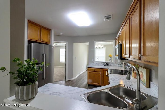 9003 Falcon Crest Ct Unit 104, Louisville, KY 40219 - kitchen featuring stainless steel appliances, brown cabinetry, a chandelier, and dark wood-type flooring