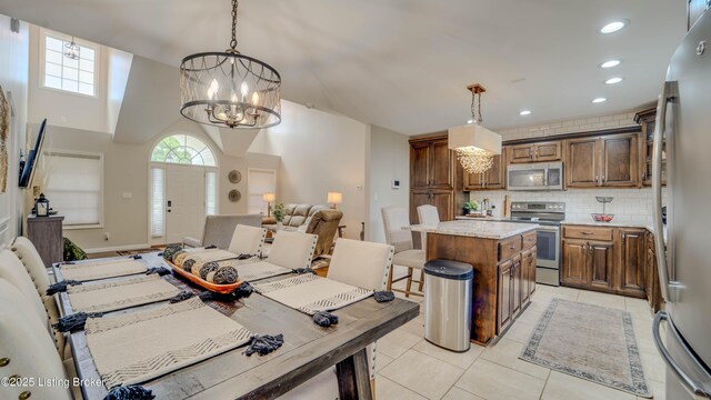 116 N Howard St, Bardstown, KY 40004 - kitchen featuring appliances with stainless steel finishes, a chandelier, backsplash, light tile patterned floors, and a center island