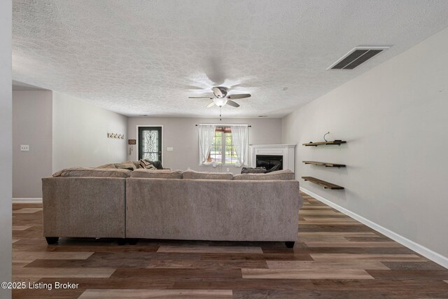 606 Lone Oak Rd, Clarkson, KY 42726 - living room featuring a ceiling fan, a textured ceiling, dark wood-type flooring, and a glass covered fireplace