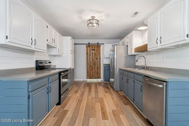 606 Lone Oak Rd, Clarkson, KY 42726 - kitchen featuring appliances with stainless steel finishes, blue cabinetry, a barn door, and white cabinets