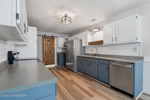 606 Lone Oak Rd, Clarkson, KY 42726 - kitchen featuring appliances with stainless steel finishes, light wood finished floors, white cabinetry, a barn door, and a textured ceiling