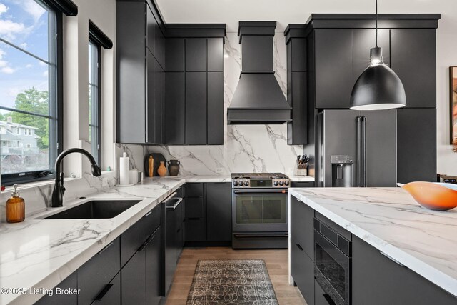 104 Howard Ln, Jeffersonville, IN 47130 - kitchen featuring appliances with stainless steel finishes, custom exhaust hood, dark cabinetry, light wood-type flooring, and pendant lighting