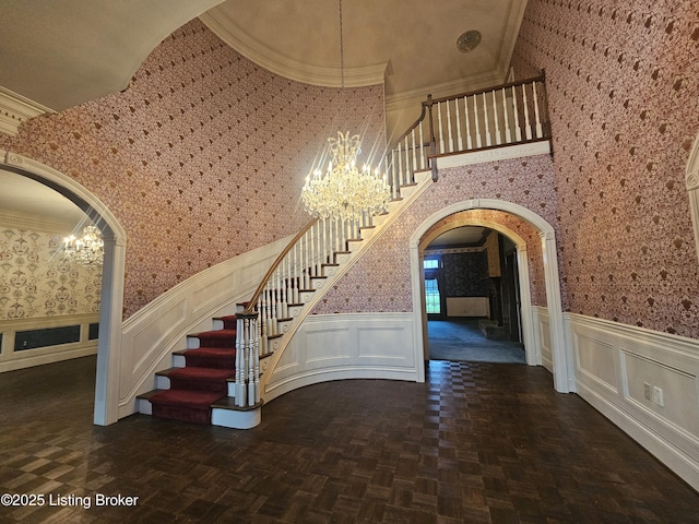 3501 Trinidad Ct, Lexington, KY 40509 - staircase featuring arched walkways, a chandelier, wallpapered walls, a wainscoted wall, and a decorative wall