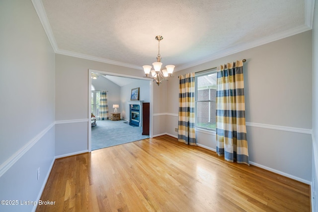 8415 Hurstbourne Woods Pl, Louisville, KY 40299 - unfurnished room with a chandelier, a textured ceiling, light wood finished floors, a glass covered fireplace, and ornamental molding