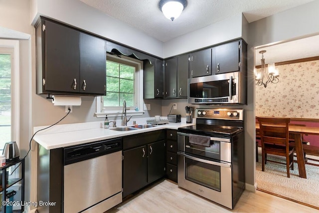2312 Blevins Gap Rd, Louisville, KY 40272 - kitchen with stainless steel appliances, light wood finished floors, light countertops, dark cabinets, and a textured ceiling