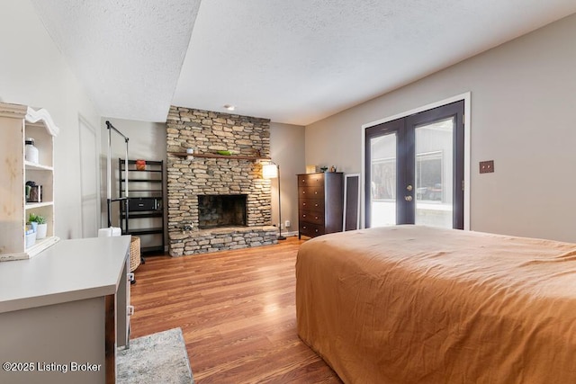 2312 Blevins Gap Rd, Louisville, KY 40272 - bedroom featuring french doors, light wood finished floors, a textured ceiling, a fireplace, and access to outside