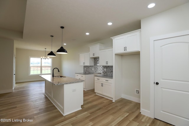 838 Otter Creek Rd, Vine Grove, KY 40175 - kitchen featuring backsplash, light wood finished floors, white cabinets, a center island with sink, and decorative light fixtures