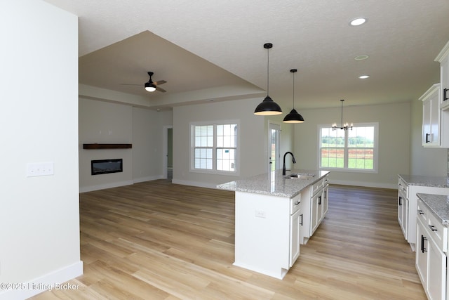 838 Otter Creek Rd, Vine Grove, KY 40175 - kitchen with light wood-type flooring, a ceiling fan, recessed lighting, white cabinets, and a glass covered fireplace