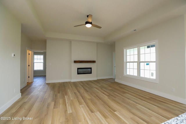 838 Otter Creek Rd, Vine Grove, KY 40175 - unfurnished living room with light wood finished floors, a ceiling fan, a glass covered fireplace, and a raised ceiling