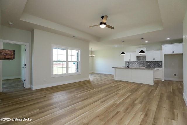 838 Otter Creek Rd, Vine Grove, KY 40175 - unfurnished living room with a raised ceiling, recessed lighting, a ceiling fan, light wood-style floors, and a chandelier