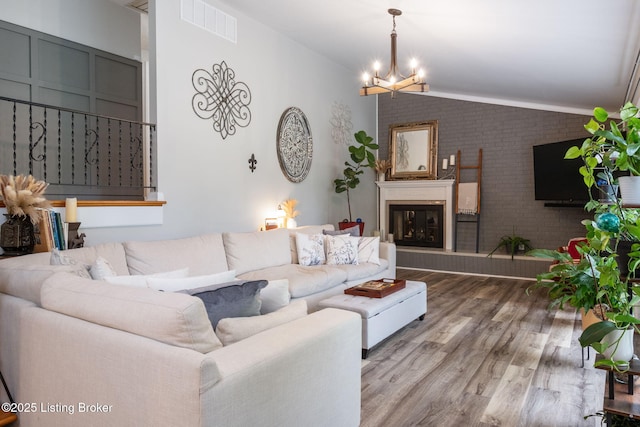 8504 Bambi Way, Louisville, KY 40214 - living room with vaulted ceiling, brick wall, a chandelier, wood finished floors, and a glass covered fireplace