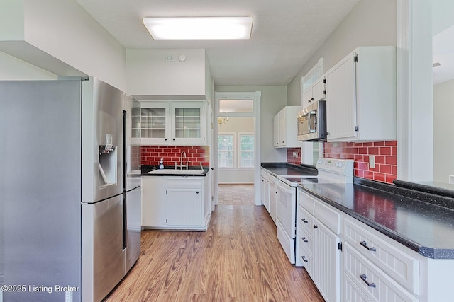 6301 Innisbrook Dr, Prospect, KY 40059 - kitchen featuring stainless steel appliances, dark countertops, backsplash, white cabinetry, and light wood-style floors