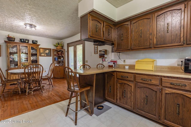 2149 Shrewsbury Rd, Leitchfield, KY 42754 - kitchen featuring light countertops, a textured ceiling, backsplash, a breakfast bar area, and a peninsula