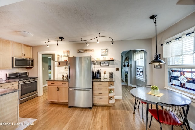 3119 Bobolink Rd, Louisville, KY 40213 - kitchen featuring appliances with stainless steel finishes, light brown cabinets, arched walkways, light wood finished floors, and a textured ceiling