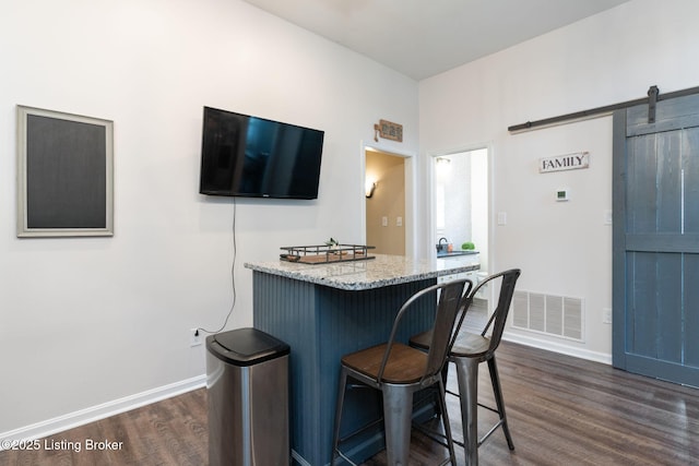 835 Forrest St, Louisville, KY 40217 - kitchen featuring dark wood-style flooring, a kitchen breakfast bar, a barn door, and light stone counters