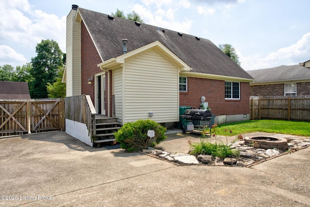 11208 Hasbrook Ct, Louisville, KY 40229 - rear view of house with brick siding, a fire pit, a shingled roof, a chimney, and a patio
