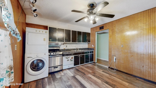 116 E Southern Heights Ave, Louisville, KY 40214 - kitchen with stainless steel range with gas stovetop, stacked washer / dryer, dark countertops, wood finished floors, and ceiling fan
