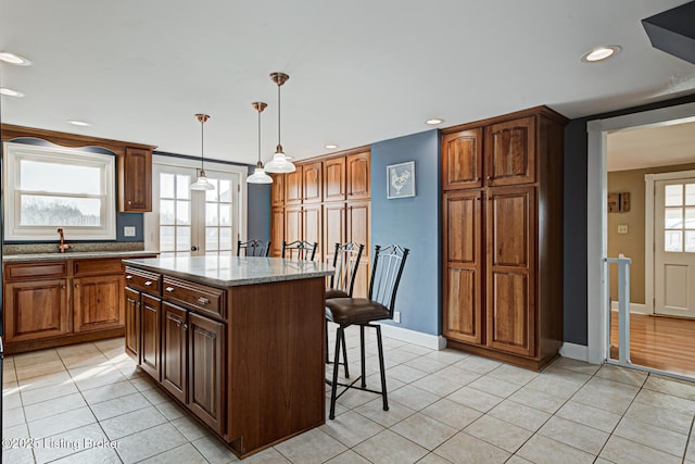 3591 Bardstown Rd, Lawrenceburg, KY 40342 - kitchen featuring a breakfast bar area, light tile patterned flooring, light stone countertops, a kitchen island, and decorative light fixtures