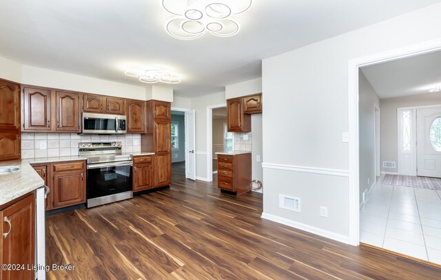 8613 Whipps Bend Rd, Bellemeade, KY 40222 - kitchen with stainless steel appliances, backsplash, dark wood finished floors, and brown cabinetry