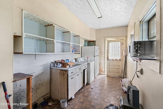 1736 W Gaulbert Ave, Louisville, KY 40210 - kitchen featuring washer / dryer, light countertops, a textured ceiling, and white cabinets