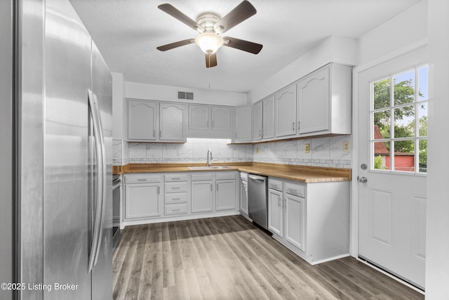 6325 Hackberry Way, Louisville, KY 40229 - kitchen featuring stainless steel appliances, wood finished floors, backsplash, ceiling fan, and a textured ceiling