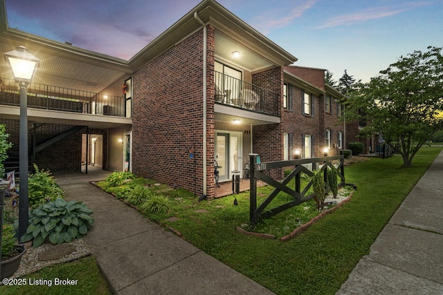 6711 Gunston Ln Unit H10, Prospect, KY 40059 - property exterior at dusk featuring a balcony, brick siding, and a lawn