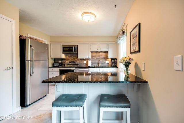 7327 Sideoats Dr, Crestwood, KY 40014 - kitchen with appliances with stainless steel finishes, a peninsula, backsplash, white cabinets, and dark stone countertops