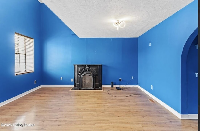2215 W Jefferson St, Louisville, KY 40212 - unfurnished living room featuring a textured ceiling, wood finished floors, arched walkways, and a fireplace