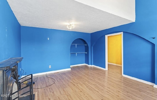 2215 W Jefferson St, Louisville, KY 40212 - unfurnished living room with wood finished floors, a textured ceiling, and arched walkways