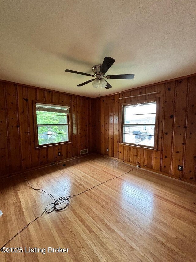 2707 Sharon Way, Louisville, KY 40220 - spare room with light wood-type flooring, plenty of natural light, a textured ceiling, wooden walls, and a ceiling fan