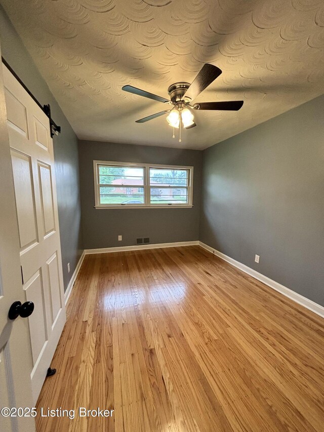 2707 Sharon Way, Louisville, KY 40220 - unfurnished room with light wood-style floors, a ceiling fan, and a barn door
