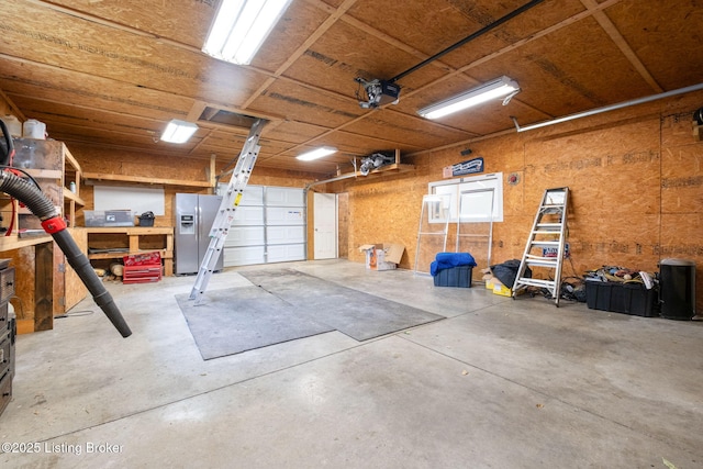 7210 River Rd, Prospect, KY 40059 - garage featuring stainless steel fridge, a garage door opener, and a workshop area
