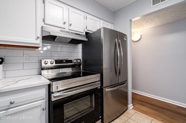 1251 Westlynne Way Apt 2, Louisville, KY 40222 - kitchen featuring stainless steel appliances, under cabinet range hood, white cabinets, tasteful backsplash, and light tile patterned floors