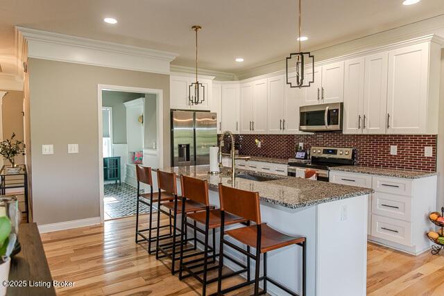 2370 N Borcherding Rd, Madison, IN 47250 - kitchen featuring appliances with stainless steel finishes, a kitchen bar, white cabinets, backsplash, and ornamental molding