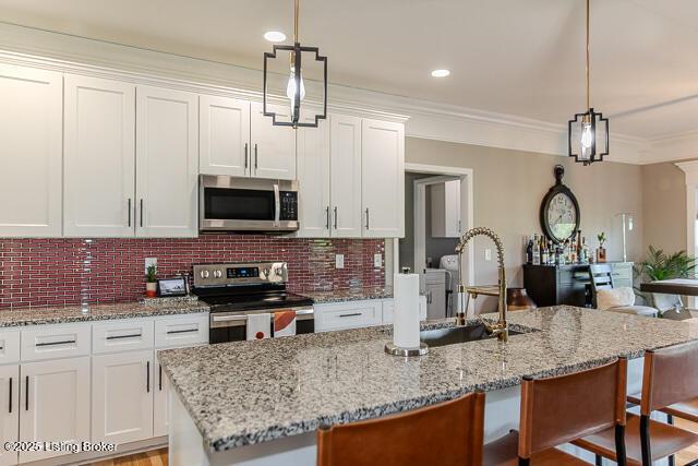 2370 N Borcherding Rd, Madison, IN 47250 - kitchen with appliances with stainless steel finishes, a kitchen breakfast bar, white cabinets, crown molding, and light stone counters