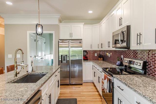 2370 N Borcherding Rd, Madison, IN 47250 - kitchen featuring appliances with stainless steel finishes, white cabinets, light wood-type flooring, backsplash, and pendant lighting