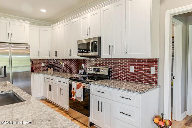 2370 N Borcherding Rd, Madison, IN 47250 - kitchen featuring appliances with stainless steel finishes, white cabinetry, light stone countertops, and backsplash