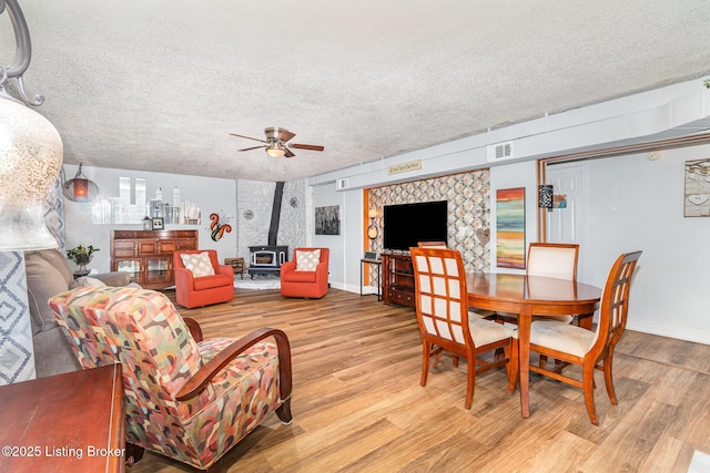 4906 Roman Dr, Louisville, KY 40291 - dining room featuring a wood stove, light wood-type flooring, a ceiling fan, and a textured ceiling