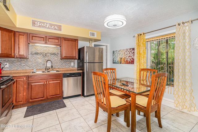 4906 Roman Dr, Louisville, KY 40291 - kitchen featuring appliances with stainless steel finishes, a textured ceiling, decorative backsplash, light countertops, and brown cabinetry