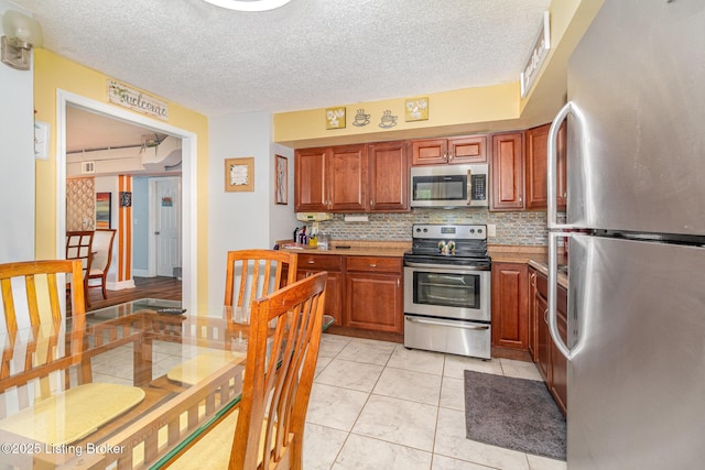 4906 Roman Dr, Louisville, KY 40291 - kitchen featuring stainless steel appliances, backsplash, light countertops, a textured ceiling, and brown cabinets