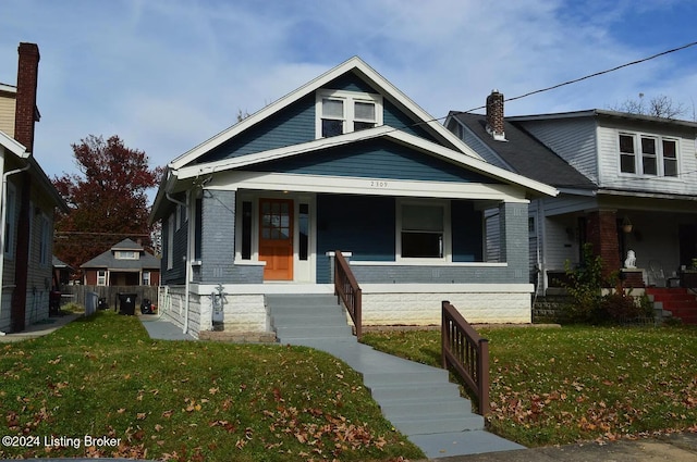 2309 Hale Ave, Louisville, KY 40210 - view of front facade with covered porch, a front lawn, a chimney, and brick siding