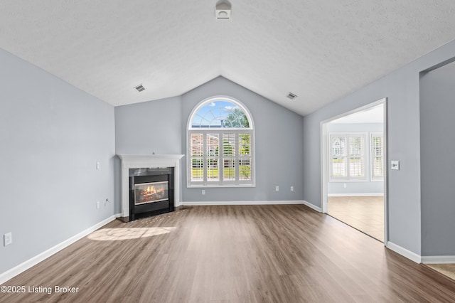 4331 Ivy Crest Cir, Louisville, KY 40241 - unfurnished living room featuring wood finished floors, a glass covered fireplace, vaulted ceiling, healthy amount of natural light, and a textured ceiling
