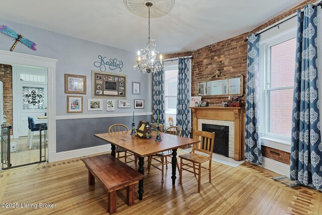 1331 Highland Ave, Louisville, KY 40204 - dining area with wood-type flooring, a chandelier, healthy amount of natural light, a fireplace, and brick wall