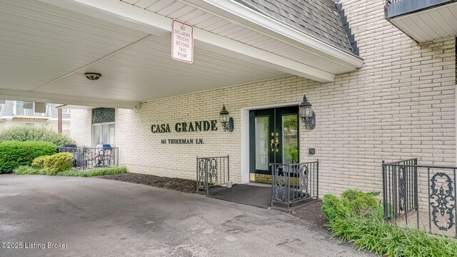 161 Thierman Ln Apt 1E, Louisville, KY 40207 - property entrance with brick siding, a carport, and a shingled roof