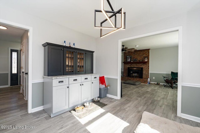 570 Sulphur Rd, Smiths Grove, KY 42171 - kitchen with light wood-style floors, glass insert cabinets, a fireplace, a ceiling fan, and white cabinets
