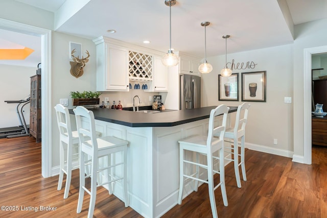12812 Ridgemoor Dr, Prospect, KY 40059 - kitchen with stainless steel fridge with ice dispenser, dark countertops, a kitchen bar, dark wood-style flooring, and white cabinetry