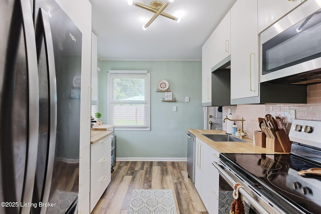 1301 Mark Trail Rd, Louisville, KY 40242 - kitchen with stainless steel appliances, light wood-style flooring, decorative backsplash, ornamental molding, and white cabinetry