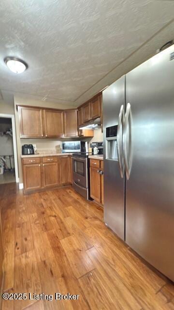360 Grant Ridge Rd, Leitchfield, KY 42754 - kitchen featuring stainless steel appliances, light wood-style flooring, brown cabinetry, and under cabinet range hood