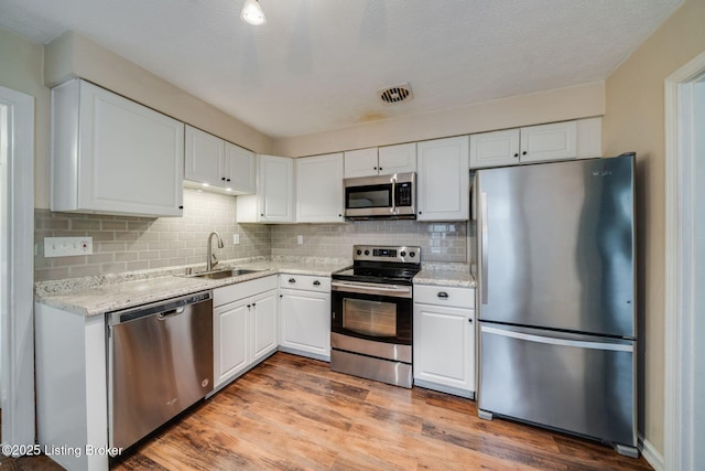 4229 Hillbrook Dr, Louisville, KY 40220 - kitchen with stainless steel appliances, white cabinetry, decorative backsplash, and light wood-type flooring